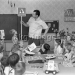 Berlin 30.06.1986 Verkehrserziehung im Kindergarten Mendelsohnstrasse. Polizist / Polizeibeamter / Volkspolizist erkärt Gruppe / Kindergartengruppe das Verkehrsschild Fussgängerüberweg. Auf dem Tisc